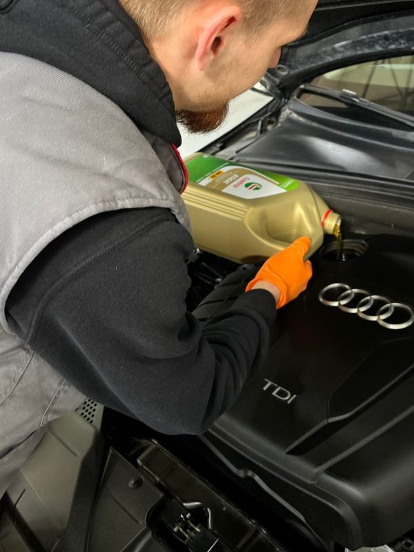 Automehaničar mijenja motorno ulje u automobilu marke Audi.