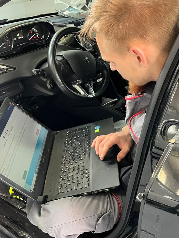 Automehaničar dijagnosticira kvar u automobilu marke Peugeot.