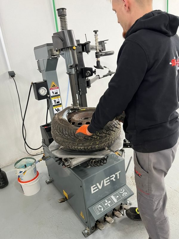 Automehaničar stavlja gumu na felgu.