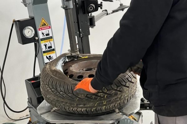 SHIFT autoservis-Slika30 Automehaničar stavlja gumu na čeličnu felgu na modernom alatu.